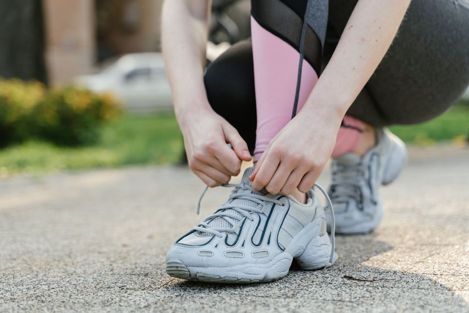 Woman tying shoelaces on sneakers before a run in the park.