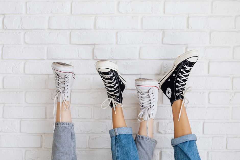 Stylish Converse sneakers against a white brick wall, showcasing casual fashion and youthful style.