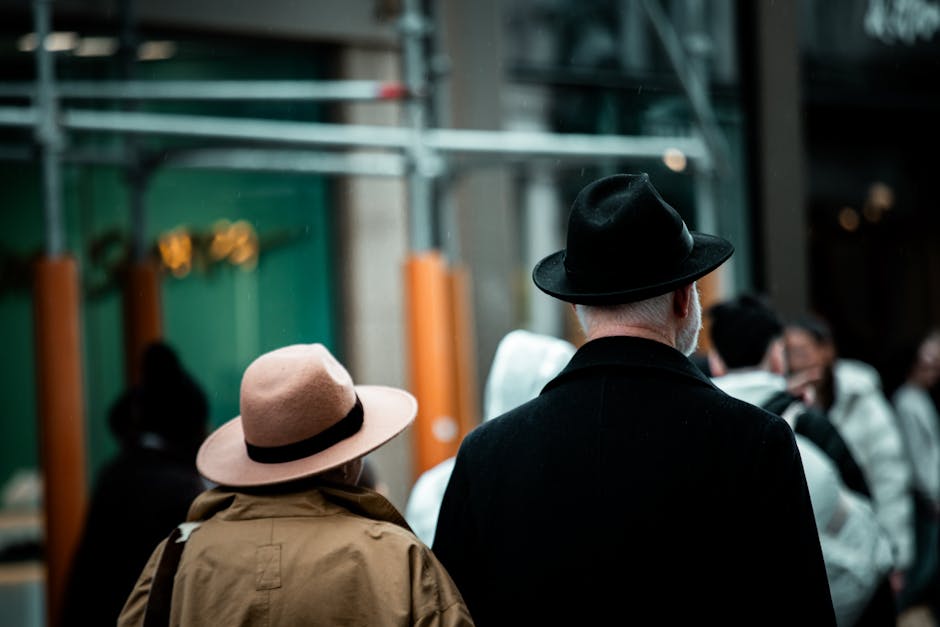 An elegant couple walking in an urban street, showcasing classic fashion with hats and coats.