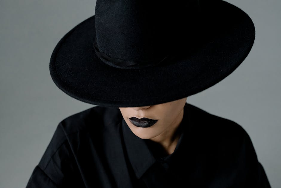 Portrait of a woman in a wide-brimmed black hat, wearing black lipstick, creating a mysterious vibe.