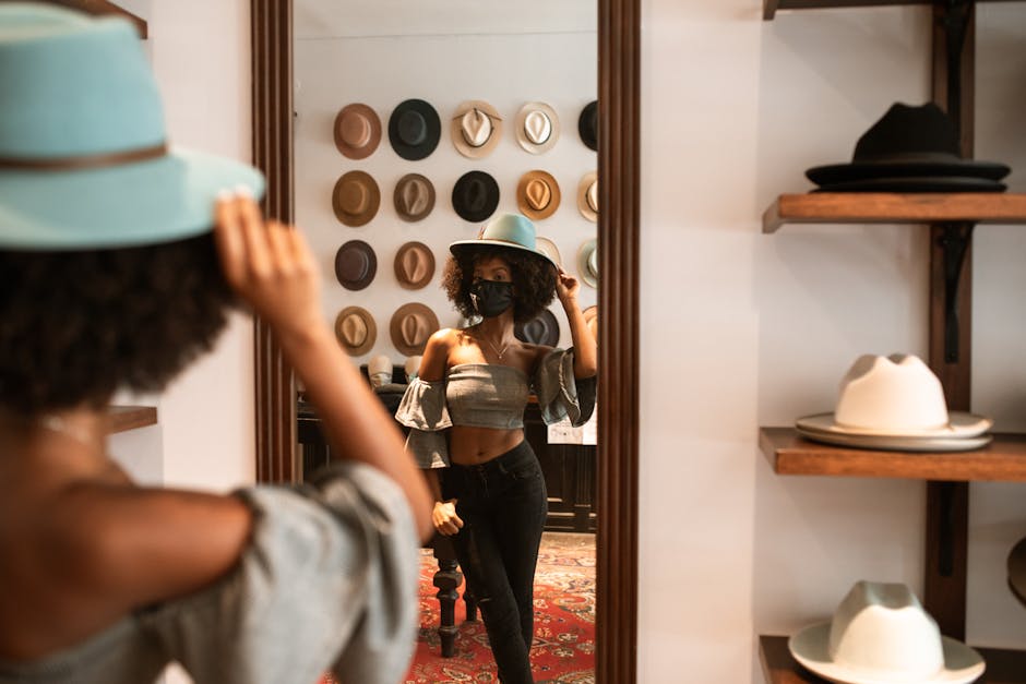 Stylish woman wearing a hat and mask, reflecting in a store mirror with wall display of hats.