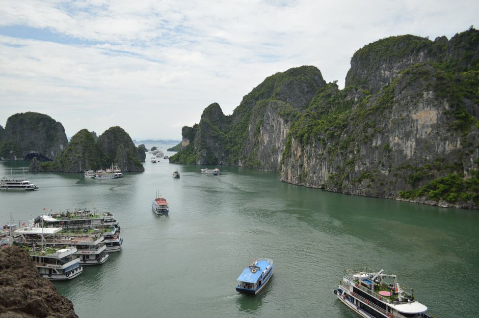 Picturesque Ha Long Bay with cruise boats navigating emerald waters among limestone karsts.