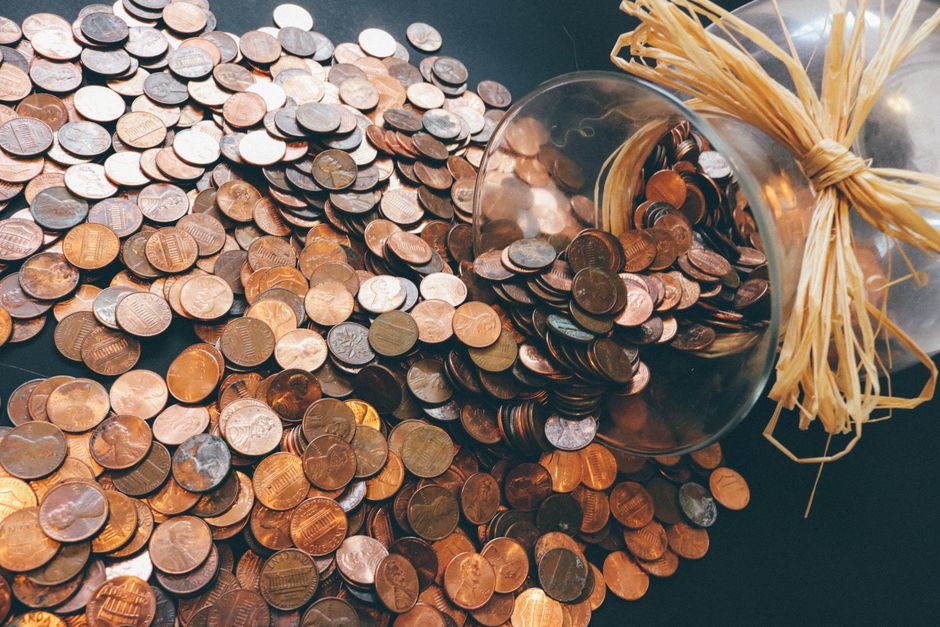 Spilled jar of pennies creating a pattern of coins representing savings and finance.