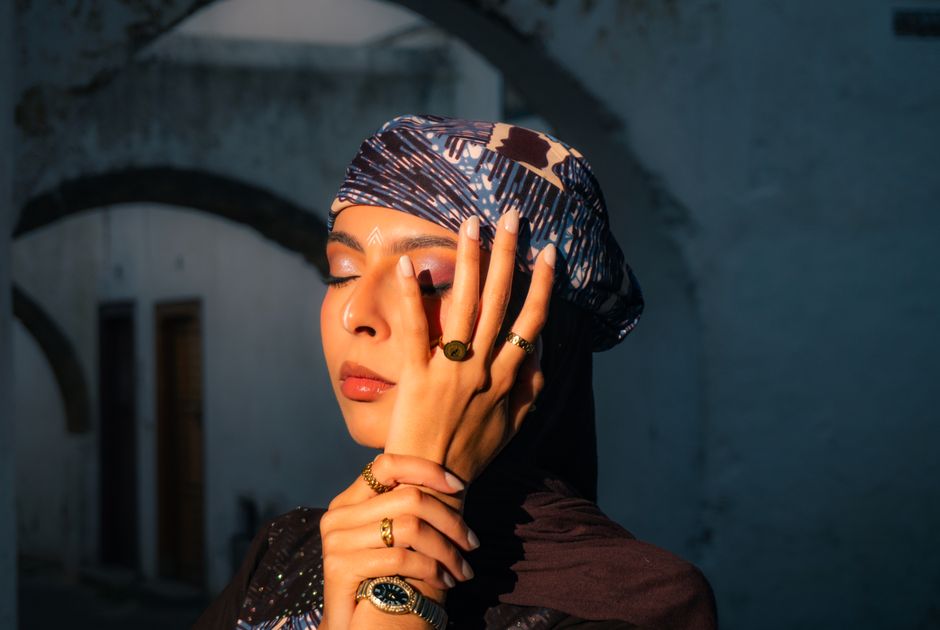 Elegant woman with jewelry posing in Casablanca, illuminated by dramatic lighting, wearing traditional Moroccan attire.
