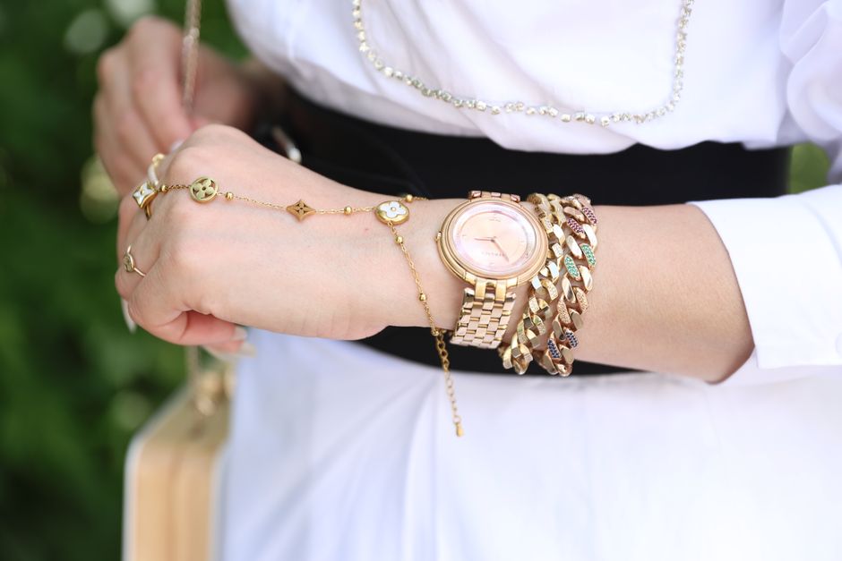 Close-up of a woman's wrist featuring elegant gold jewelry and a wristwatch. Stylish and sophisticated.