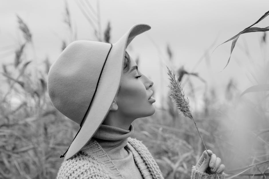 Black and white profile portrait of a woman with a hat, embracing tranquility in a field.