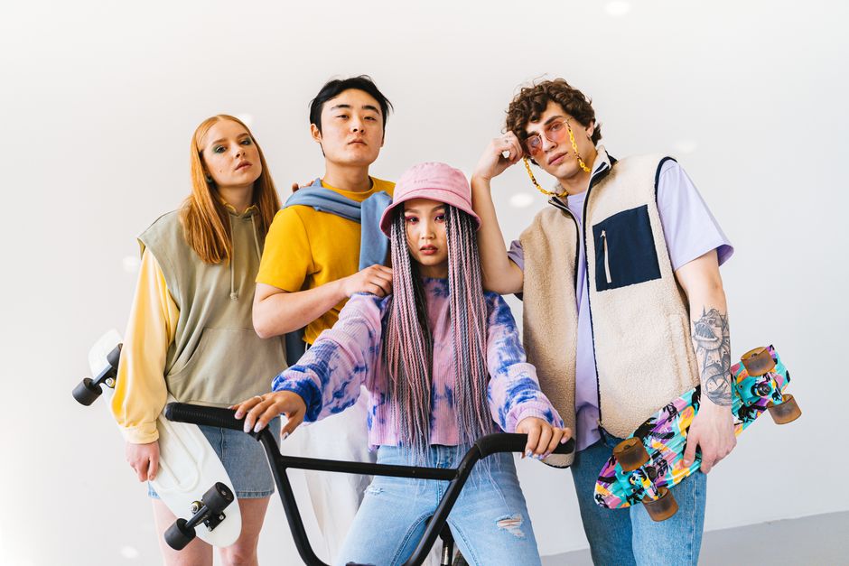 Four stylish friends posing with skateboards and a bicycle, showcasing modern fashion.