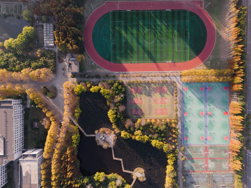 An aerial view of a vibrant sports complex in Nanjing, showcasing lush greenery and athletic fields.