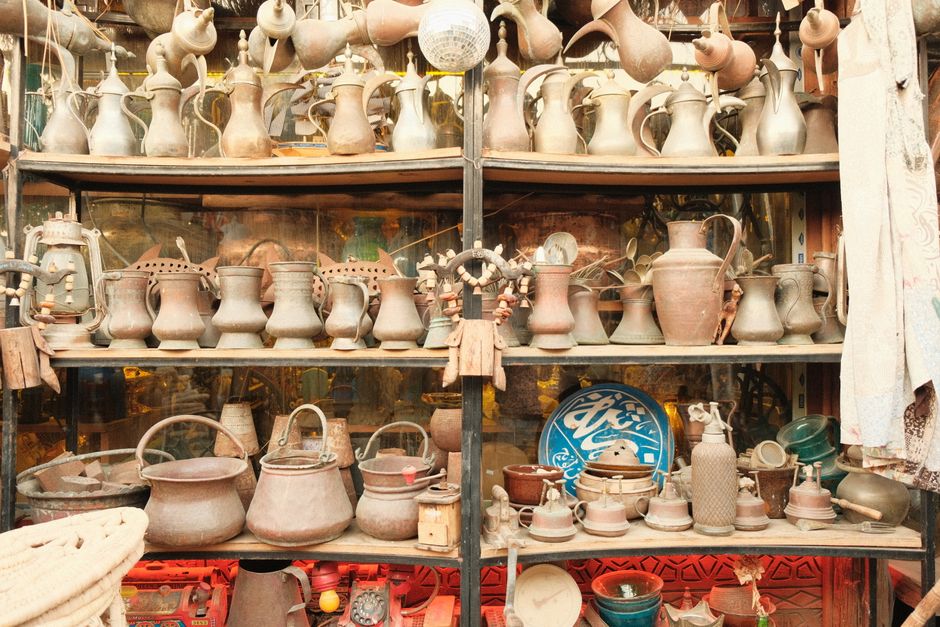 Vintage metal pots and jugs displayed in a traditional market setting.
