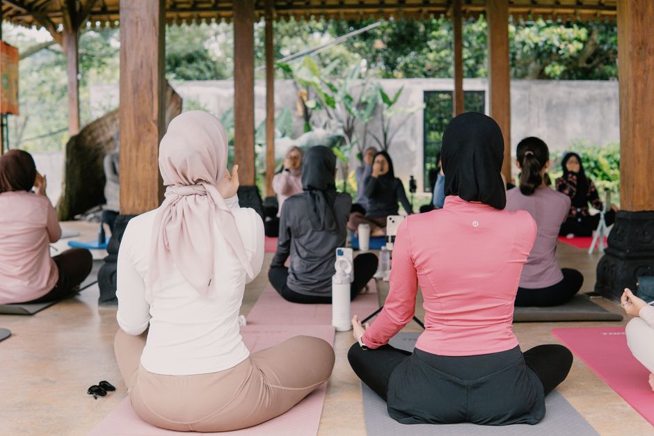 A serene outdoor yoga class with women practicing meditative poses, surrounded by nature in Indonesia.
