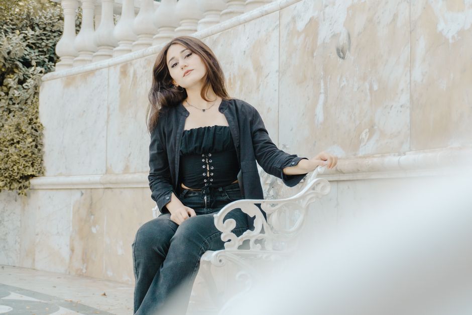 Portrait of a woman seated on a decorative bench, exuding elegance in a serene outdoor setting in Baku, Azerbaijan.