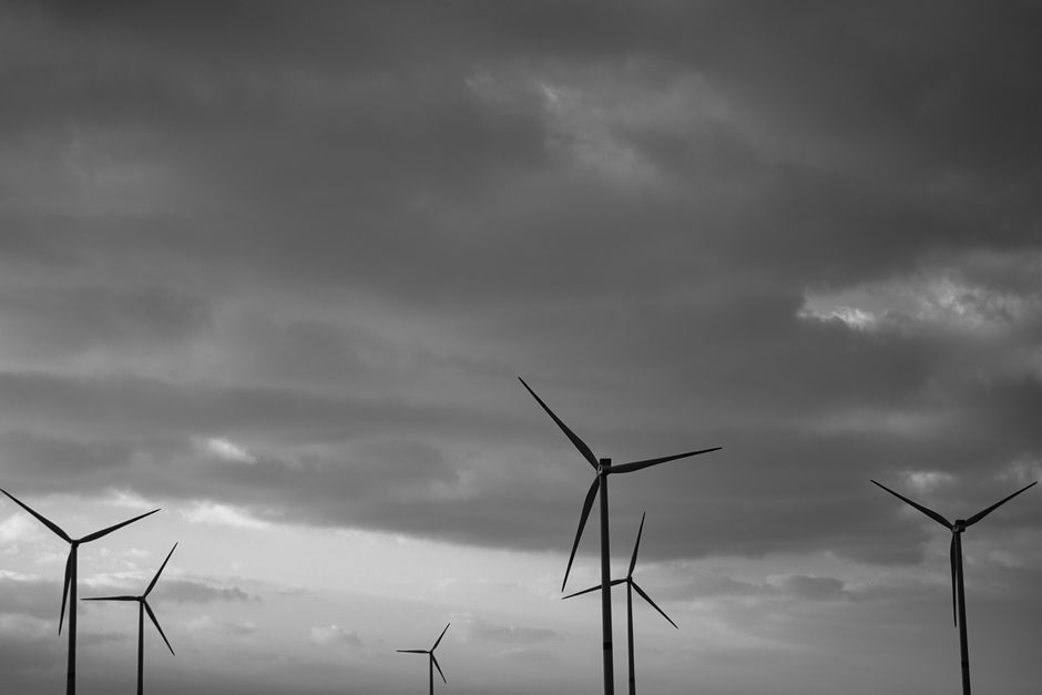 Silhouetted wind turbines under a dramatic cloudy sky, symbolizing renewable energy.