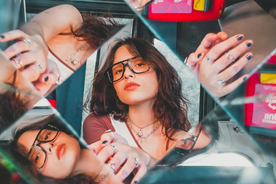 Artistic portrait of a woman using mirrors for creative reflections, highlighting unique style.
