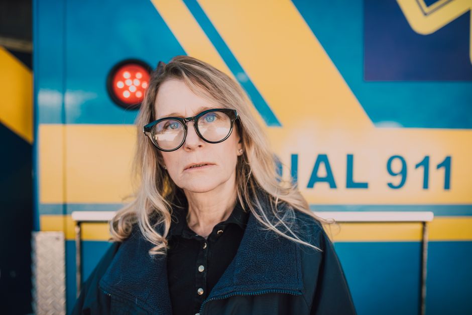 Portrait of a female paramedic in front of an ambulance vehicle.