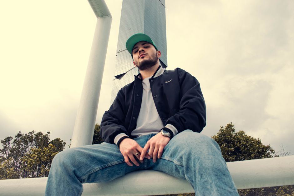 Stylish young man posing in urban setting against tall building in Puebla, Mexico.