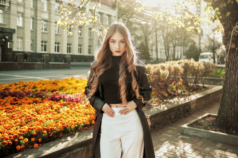 Stylish woman in urban setting with vibrant floral background during daytime.