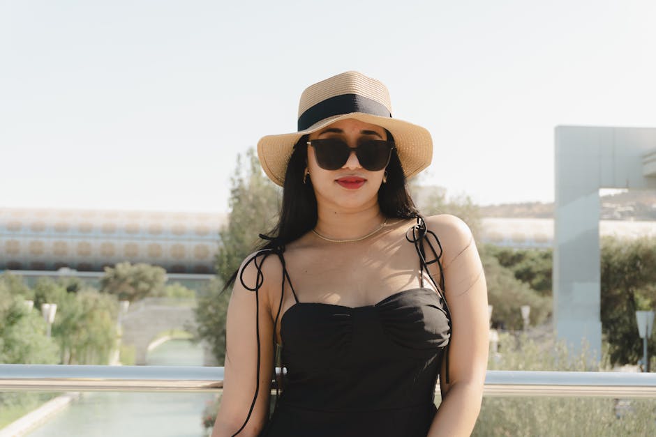 Fashionable woman wearing hat and sunglasses, enjoying a sunny day outdoors in Baku, Azerbaijan.