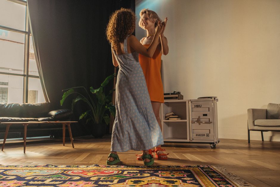 Two women share a joyful moment dancing together in a warmly lit room, showcasing love and happiness.